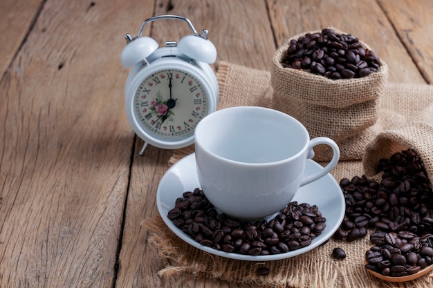 Svuoti la tazza di caffè macchiato con i chicchi di caffè isolati su fondo di legno