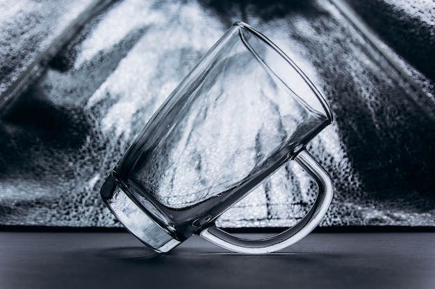 Svuoti la tazza di vetro trasparente su un primo piano d'argento grigio del fondo. tazza alta con manico e gamba.