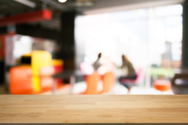 Svuoti lo scrittorio di legno sopra il fondo vago del caffè della caffetteria