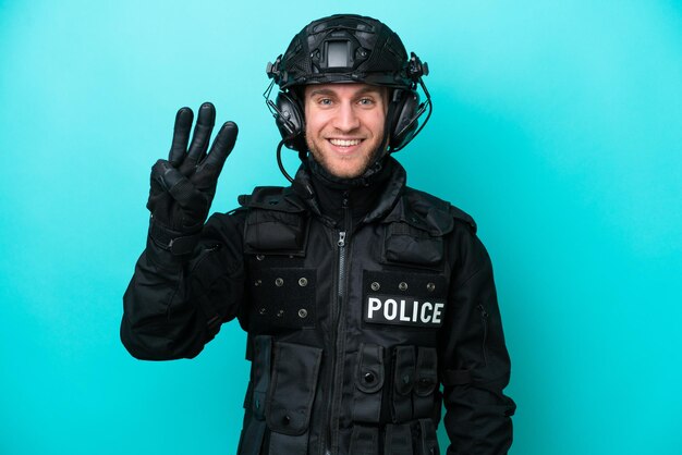 SWAT uomo caucasico isolato su sfondo blu felice e contando tre con le dita