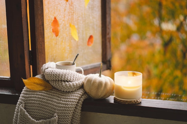 Sweet Home Natura morta dettagli in casa su una finestra di legno Maglione candela tè caldo e arredamento autunnale Arredamento per la casa autunnale Accogliente atmosfera autunnale Ringraziamento Halloween Accogliente concetto autunnale o invernale