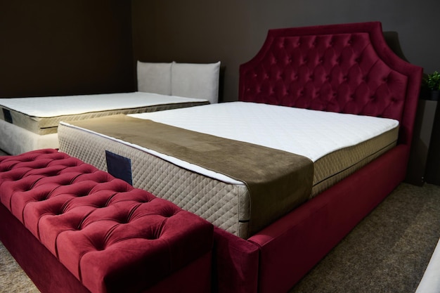 Sylish morbido letto per dormire realizzato con tappezzeria in velluto rosso con materasso ortopedico e pouf in velluto esposto per la vendita nello showroom di mobili Design della camera da letto