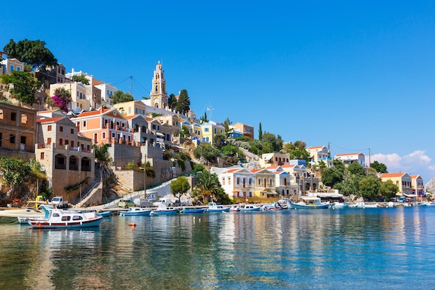 SYMI, GRECIA - GIUGNO 12,2015: Vista di una strada costiera e barche da pesca ormeggiate nel porto di Yialos il 12 giugno 2015 sull'isola di Symi, Grecia. Symi è la destinazione facile e più popolare per gite di un giorno f