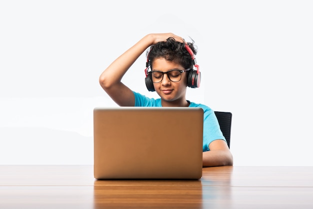 Syudent maschio indiano o bambino che studia online utilizzando il computer portatile. Bambino asiatico che frequenta la scuola online usando il computer