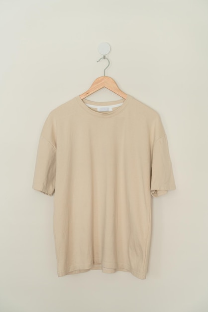 t-shirt beige appesa con appendiabiti in legno alla parete