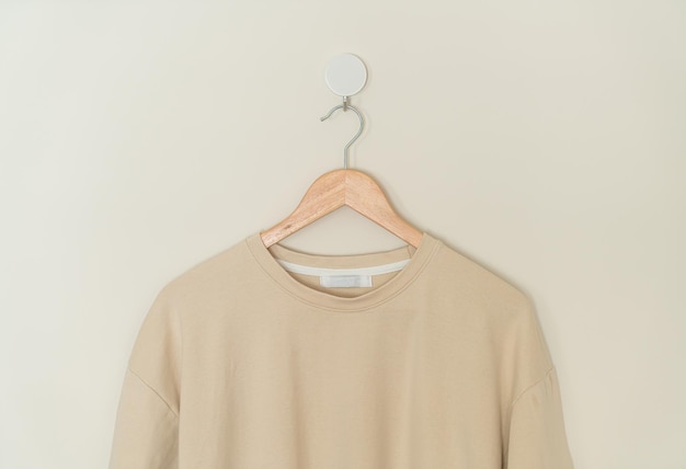 t-shirt beige appesa con appendiabiti in legno alla parete