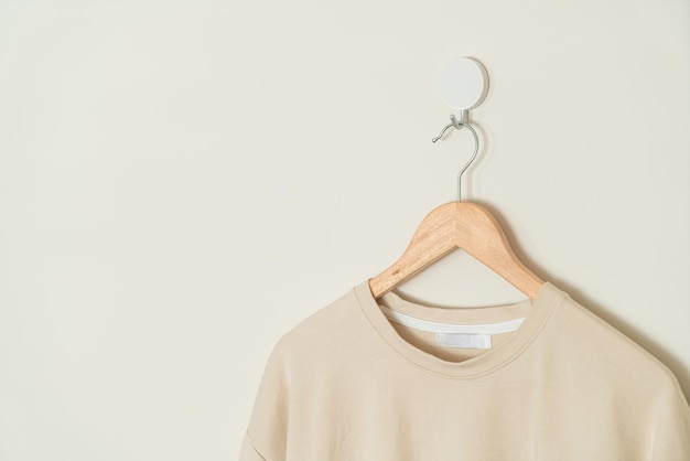 t-shirt beige appesa con appendiabiti in legno alla parete