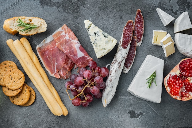 Tabella di antipasti con diversi set di antipasti, su sfondo grigio, piatto laici