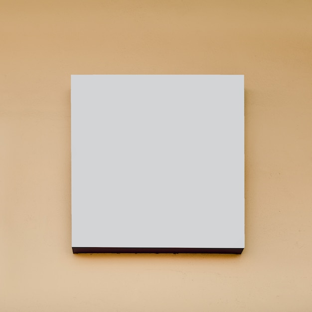 Tabellone per le affissioni di forma quadrata bianca su fondo beige