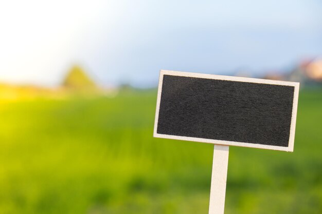 Tabellone per le affissioni nero vuoto contro il paesaggio del campo verde Modello di mockup vuoto Etichetta lavagna su terreno agricolo Copia banner spazio per il tuo testo Paesaggio agricolo Paesaggio estivo con campo collinare