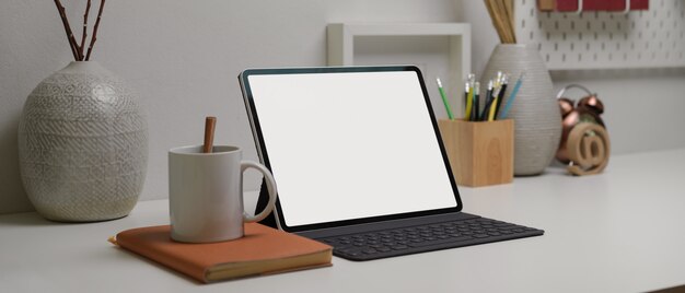 tablet con tastiera wireless sulla moderna scrivania di casa con spazio di copia, forniture e decorazioni