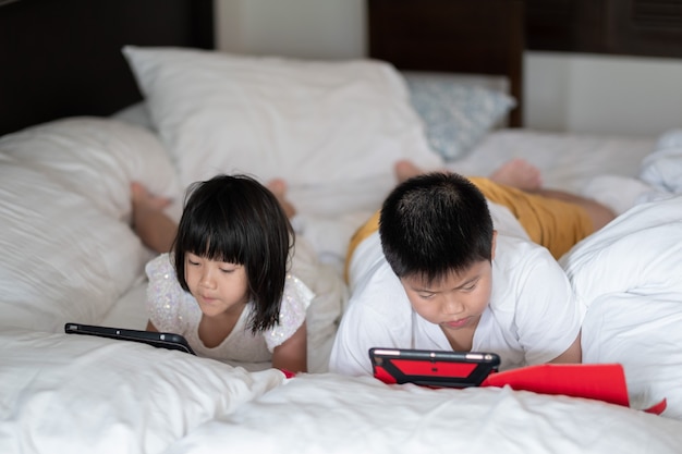 Tablet dipendente da due bambini, bambino asiatico che guarda un cartone animato