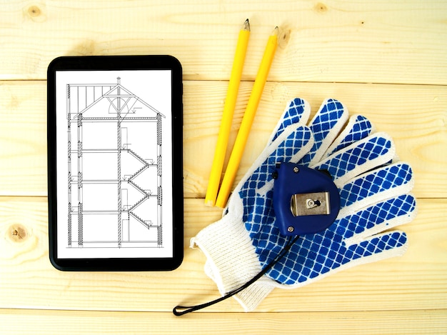 Tablet, disegni e strumenti di lavoro su un tavolo di legno.