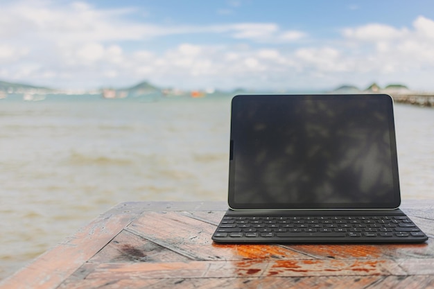 Tablet nero con tastiera sul tavolo e vista mare nel concetto di lavoro