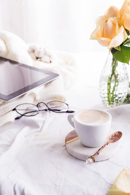 Tablet pc computer, tazza di caffè e rose beige al mattino