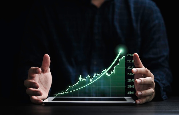 Tablet proteggi mano aziendale con grafico tecnico verde virtuale con freccia crescente per investimenti sul concetto di mercato azionario.