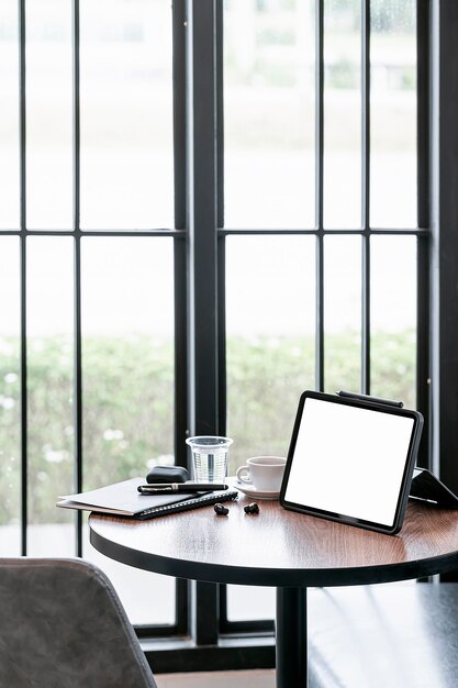 Tablet schermo vuoto e gadget sul tavolo di legno nella sala bar, vista verticale.