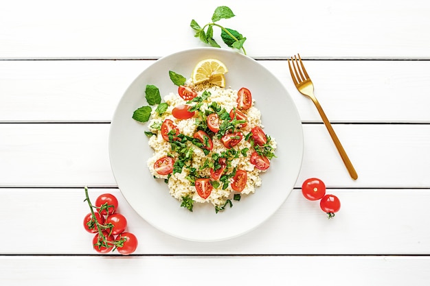 Tabouli freschi fatti in casa o insalata di tabulé vista dall'alto su superficie di legno bianca con spazio di copia