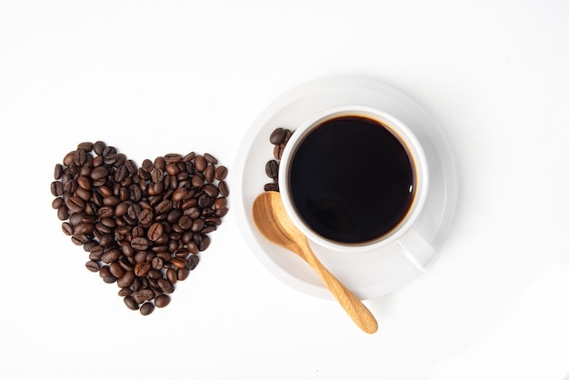 tabulare chicchi di caffè come una forma di cuore e un cucchiaio di legno su una tazza bianca di caffè caldo