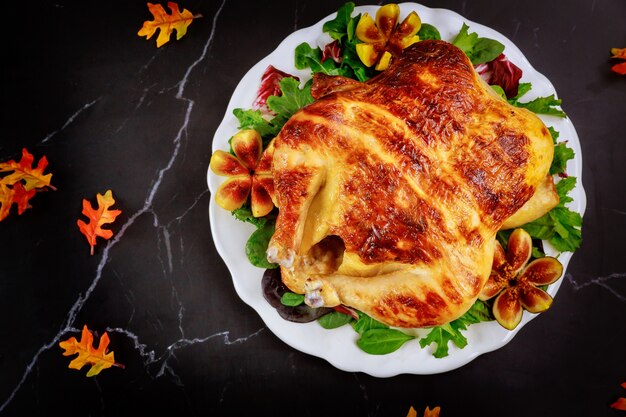 Tacchino intero arrosto con insalata su sfondo nero per il Giorno del Ringraziamento