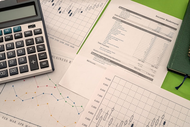 Taccuini della penna del calcolatore dei soldi dei grafici di affari che si trovano sulla tavola. Concetto di grafici