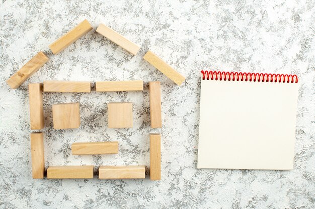 taccuino a forma di casa con blocchi di legno vista dall'alto su sfondo grigio bianco