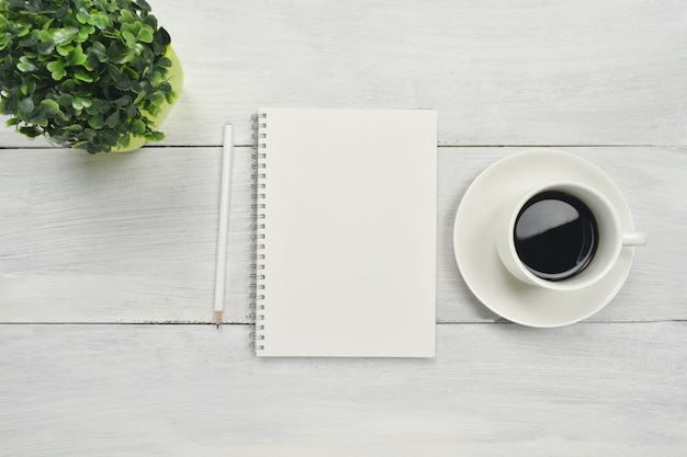 Taccuino aperto in bianco con caffè su spazio di legno.