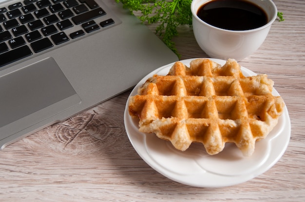 Taccuino con caffè caldo con il wafer sulla tavola di legno