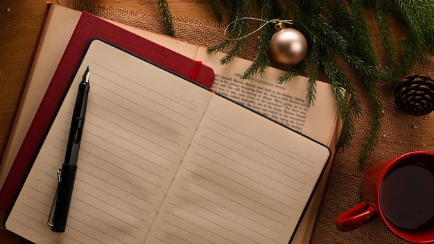 Taccuino con la tazza di caffè della penna e l'albero di Natale sulla vista superiore di concetto di Natale della tavola di legno