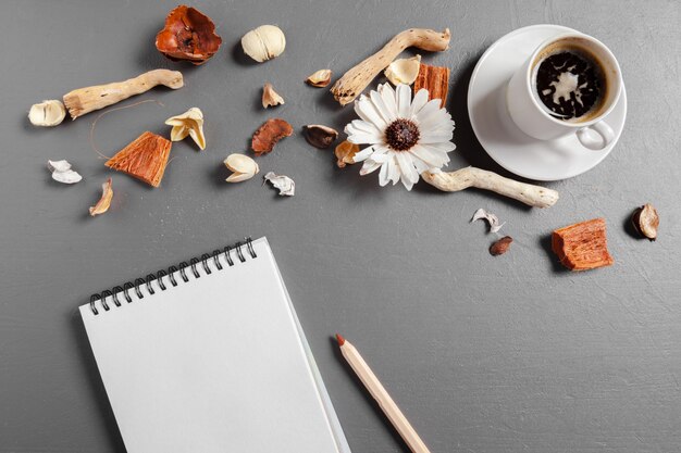 Taccuino con penna, caffè e fiori sul tavolo