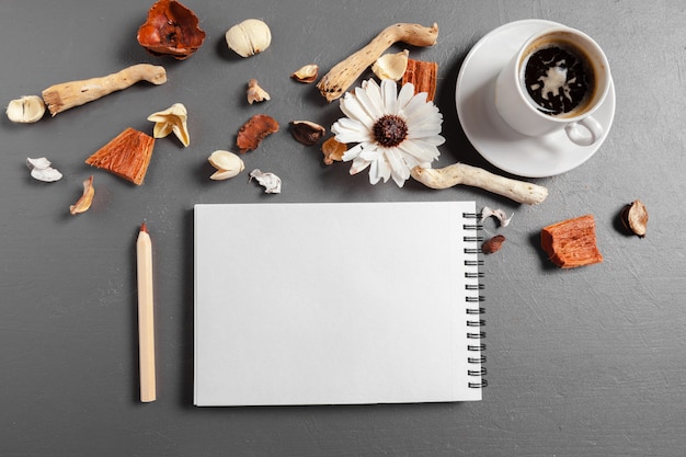 Taccuino con penna, caffè e fiori sul tavolo