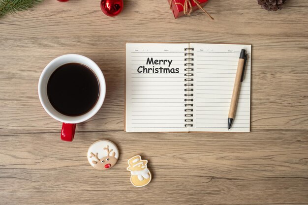 Taccuino nero tazza di caffè Biscotti di Natale e penna sul tavolo di legno Vista dall'alto e spazio di copia Natale Felice Anno Nuovo Obiettivi Risoluzione To do list Strategia e concetto di piano