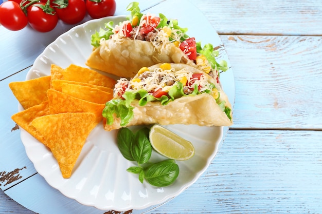 Taco gustoso con patatine nachos e verdure sul piatto sul tavolo