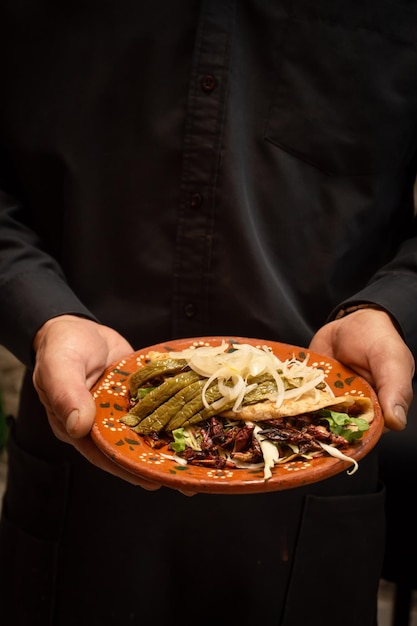 Taco messicano fatto con cavallette e verdure tenuto da cameriere irriconoscibile