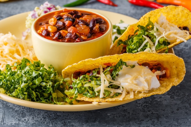 Tacos con chili con carne, insalata, formaggio e panna acida