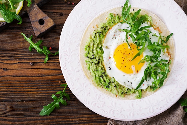 Tacos con guacamole, uovo fritto e rucola. Cibo salutare. Colazione utile. Disteso. Vista dall'alto