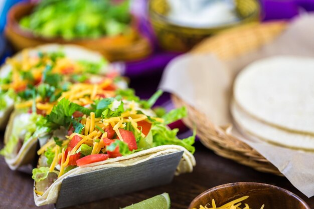 Tacos di carne macinata con lattuga romana, pomodori a cubetti e formaggio cheddar grattugiato.