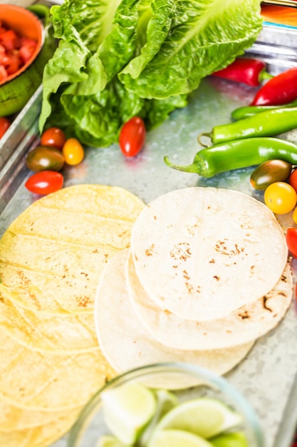 Tacos di carne macinata con lattuga romana, pomodori a dadini, ravanelli e formaggio cheddar grattugiato.