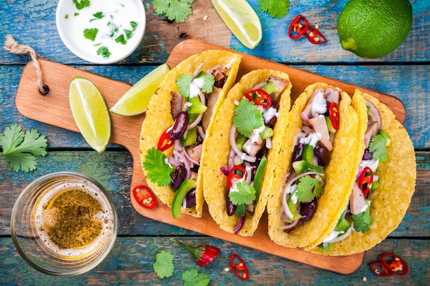 Tacos di mais con carne di maiale e verdure su un tavolo in legno vista dall'alto