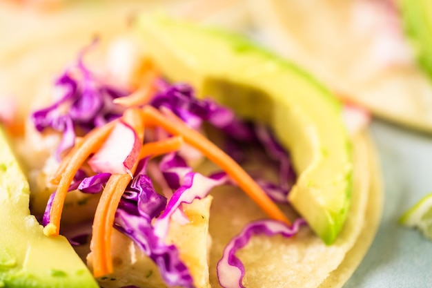 Tacos di pesce fresco con merluzzo e cavolo viola su tortillas di mais bianco.