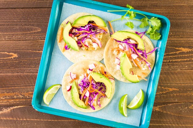 Tacos di pesce fresco con merluzzo e cavolo viola su tortillas di mais bianco.