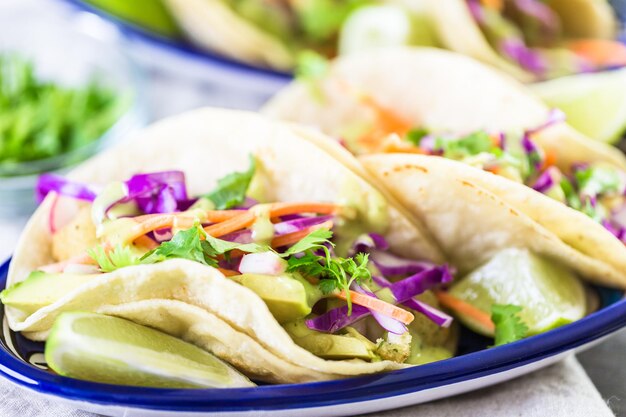 Tacos di pesce fresco con verdure e salsa guacamole su tortillas di mais bianco.