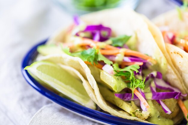 Tacos di pesce fresco con verdure e salsa guacamole su tortillas di mais bianco.