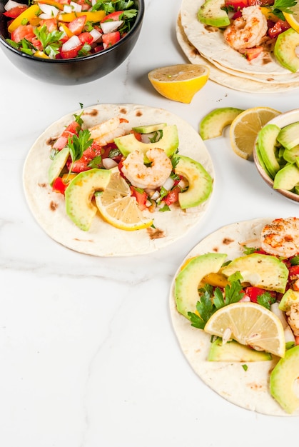 Tacos di tortilla con insalata tradizionale fatta in casa, prezzemolo, limone fresco, avocado e gamberi alla griglia