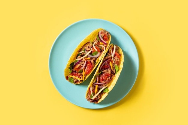 Tacos messicani tradizionali con carne e verdure su fondo giallo