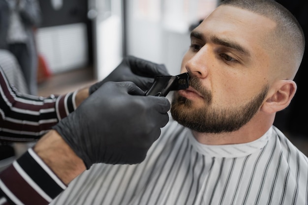 Taglia barba, baffi e capelli sulla testa del migliore amico del cliente con brutalità