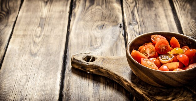 Taglia i pomodori freschi in una ciotola di legno