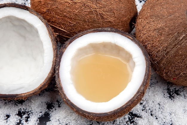 Taglia il cocco fresco con vero latte di cocco su uno sfondo di fiocchi di cocco.