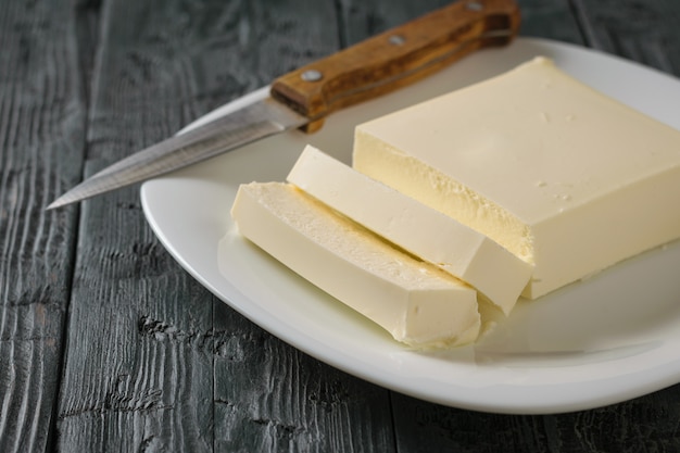 Tagliare con un coltello un pezzo di formaggio serbo su un tavolo di legno. La vista dall'alto. Prodotto lattiero-caseario. Lay piatto.