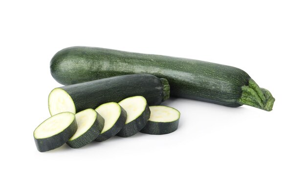 Tagliare e intere zucchine mature verdi isolate su bianco